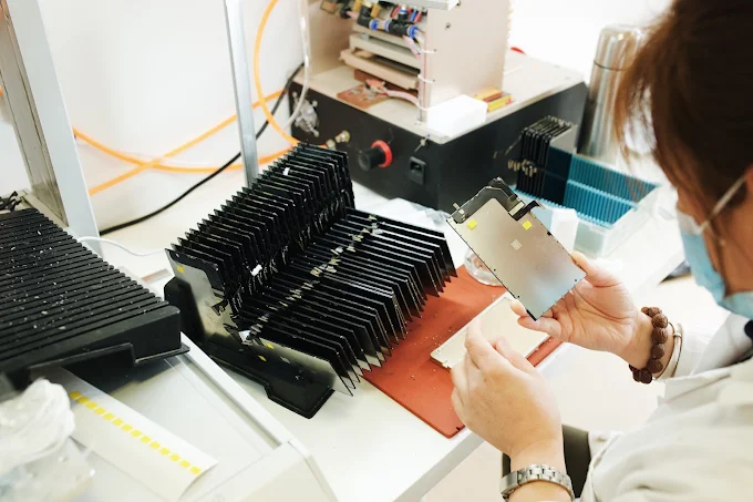 Contrôle qualité module LCD · technicienne inspectant une pile de modules Apple à l'atelier 189 rue d'Aubervilliers, Paris 18